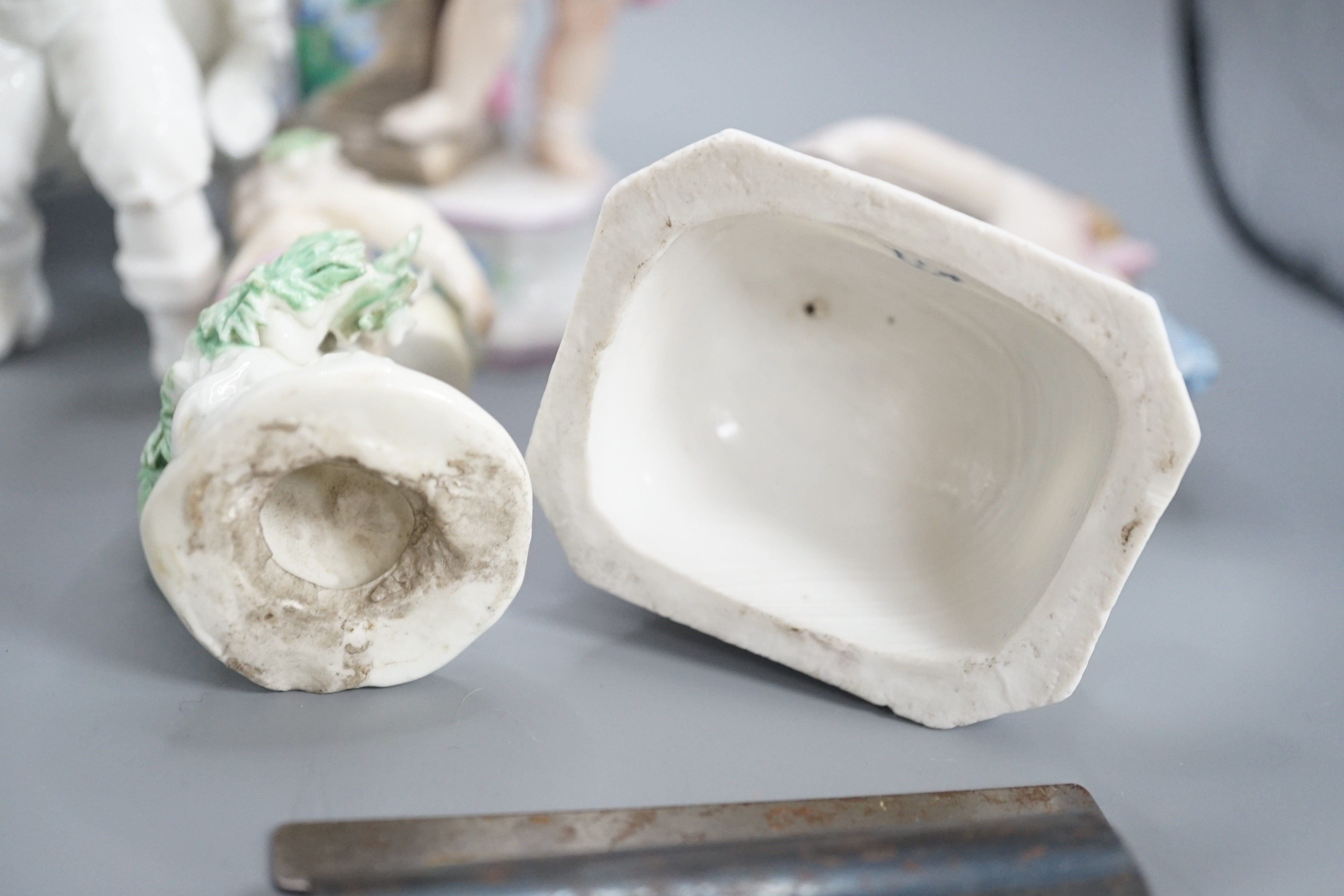 A pair of Continental porcelain cherub candlesticks, 13.5cm, a figural bonbon and a Derby figure